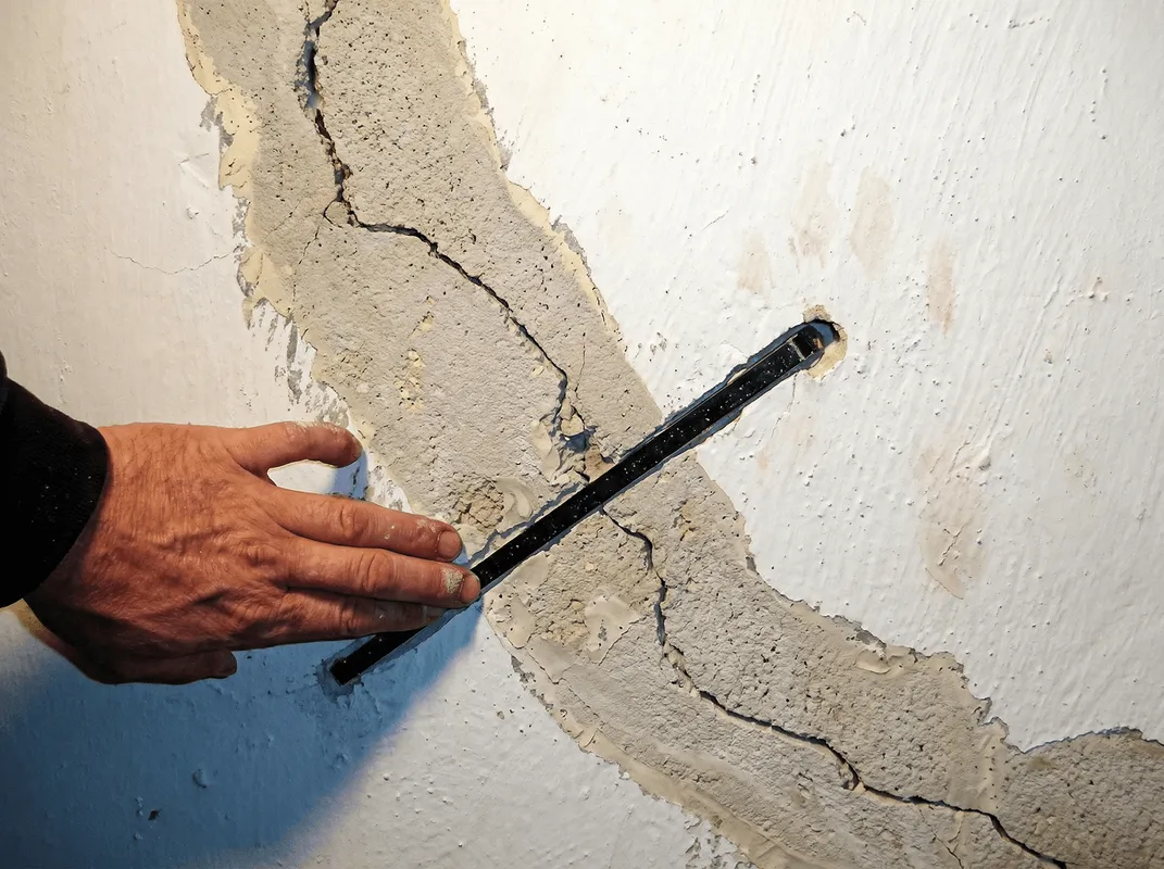A wall with a large crack is being inspected by a professional in Albany, NY